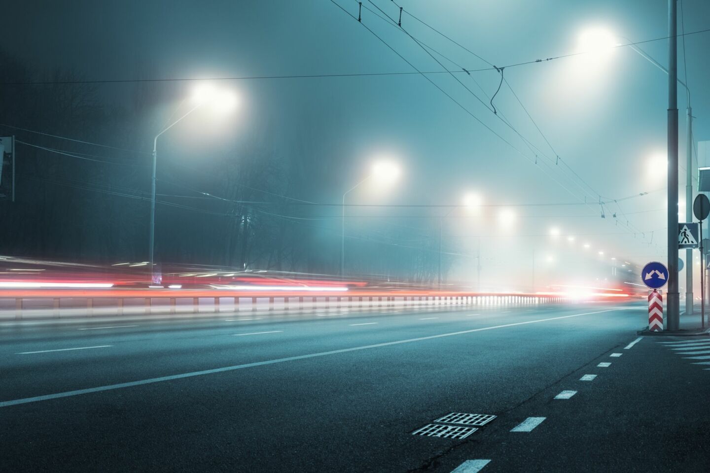 Misty blue empty stret at night with glare from bright streetlights.